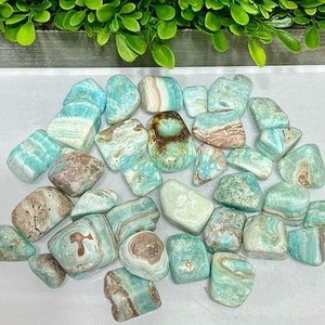 May include: A collection of tumbled blue and brown apophyllite stones. The stones are smooth and polished, with a variety of shapes and sizes.