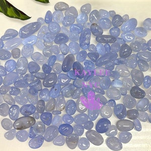 May include: A large collection of light blue chalcedony tumbled stones. The stones are smooth and polished, and they have a variety of shapes and sizes.