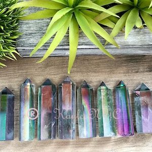 May include: Eight iridescent crystal points in various shades of green, purple, and blue. The points are arranged in a row on a wooden surface.