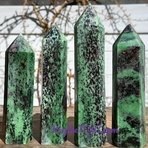 May include: Four green and black gemstone towers with a pointed top. The towers are different sizes and have a speckled pattern.