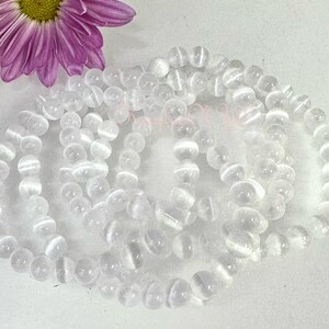 May include: A set of five white gemstone bracelets featuring a smooth, round bead design. The bracelets are crafted from white agate, a type of quartz known for its calming and grounding properties.