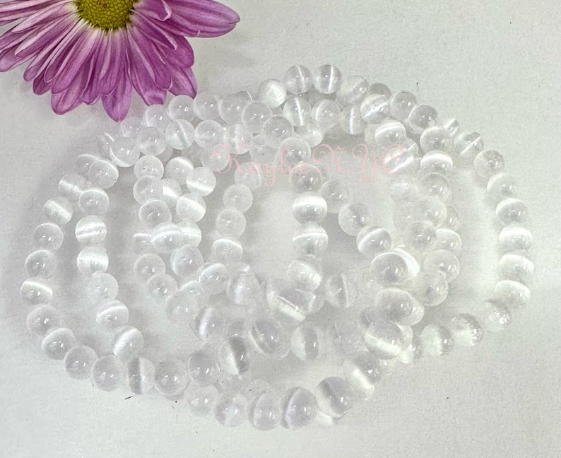 May include: A set of five white gemstone bracelets featuring a smooth, round bead design. The bracelets are crafted from white agate, a type of quartz known for its calming and grounding properties.