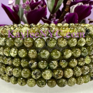 May include: A stack of green gemstone bracelets with a speckled pattern. Each bracelet is made of round beads.