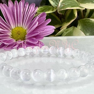 May include: A white gemstone bracelet with round beads. The bracelet is made of clear, translucent stones with a slight shimmer.