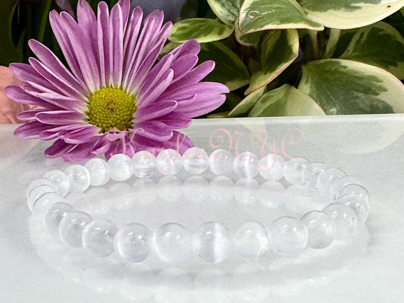 May include: A white gemstone bracelet with round beads. The bracelet is made of clear, translucent stones with a slight shimmer.