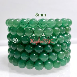 Puede incluir: Pila de ocho pulseras de jade verde, cada una con cuentas de 8 mm. Las pulseras están apiladas una encima de la otra, con la pulsera superior siendo la más visible. Las cuentas son redondas y lisas, y las pulseras están hechas de jade natural.