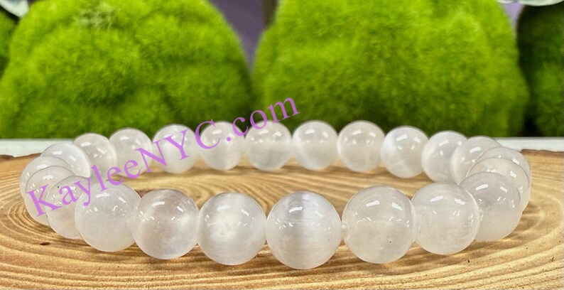 Puede incluir: Pulsera de cuentas de piedra lunar blanca con un acabado liso y pulido. Las cuentas son redondas y tienen un brillo sutil.