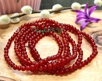 Puede incluir: Un conjunto de seis pulseras de cuentas de cornalina roja. Las pulseras están hechas de pequeñas cuentas redondas y están apiladas unas sobre otras.