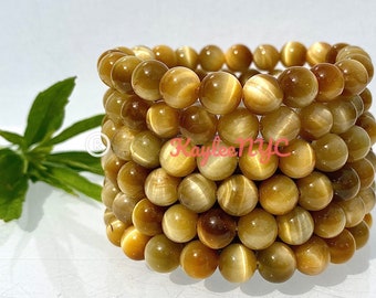 May include: A stack of golden tiger's eye bead bracelets. The beads are round and have a shimmering, iridescent effect.