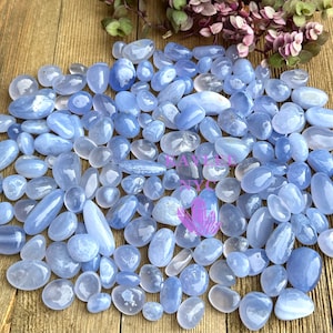 May include: A large collection of blue agate tumbled stones. The stones are smooth and polished, with a variety of shades of blue.