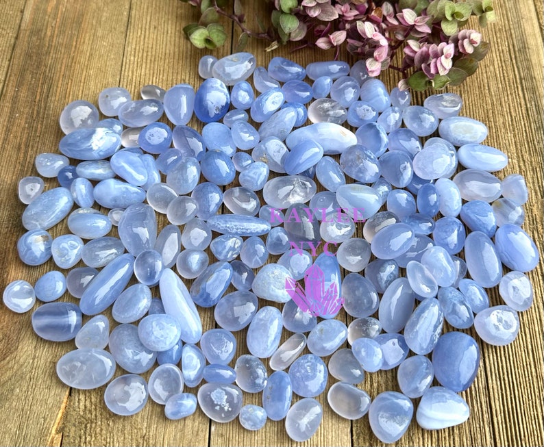 May include: A large collection of blue agate tumbled stones. The stones are smooth and polished, with a variety of shades of blue.
