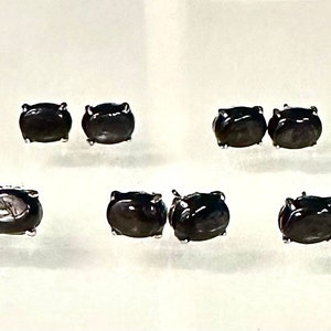 Könnte beinhalten: Sechs Paar schwarze ovale Ohrstecker. Die Ohrringe sind in Silber gefasst.