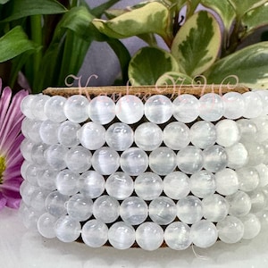 May include: A white gemstone bracelet with multiple strands of round beads. The beads have a subtle shimmer and are arranged in a stacked pattern.