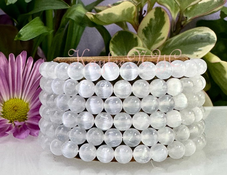 May include: A white gemstone bracelet with multiple strands of round beads. The beads have a subtle shimmer and are arranged in a stacked pattern.