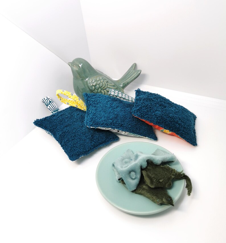 May include: Four blue and white patterned dishcloths with a yellow trim and a green ceramic bird figurine. The dishcloths are folded and arranged on a white surface.