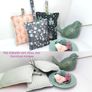 May include: Four handmade fabric sachets with a variety of patterns and colours. The sachets are filled with a soft, fluffy material and have a loop for hanging. The text "Nid d'abeille vert d'eau clair Garniture minkee" is visible in the image.