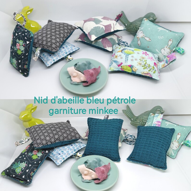 May include: A set of teal blue and black patterned fabric squares with a minky filling. The squares are arranged in a pile with a small plate of pink and blue fabric scraps in the centre. The text "Nid d'abeille bleu p&eacute;trole garniture minkee" is visible at the top of the image.