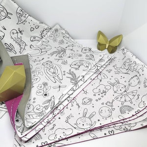 May include: A set of five white fabric triangles with black line drawings of animals and other designs. The triangles have pink stitching around the edges and are folded together.