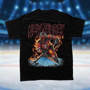 May include: Black t-shirt with a graphic of a hockey player with horns and flames, holding a hockey stick. The text "NEW JERSEY" is above the player.