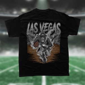 May include: Black t-shirt with a graphic of a skeleton pirate holding a football and running. The text "LAS VEGAS" is above the pirate.
