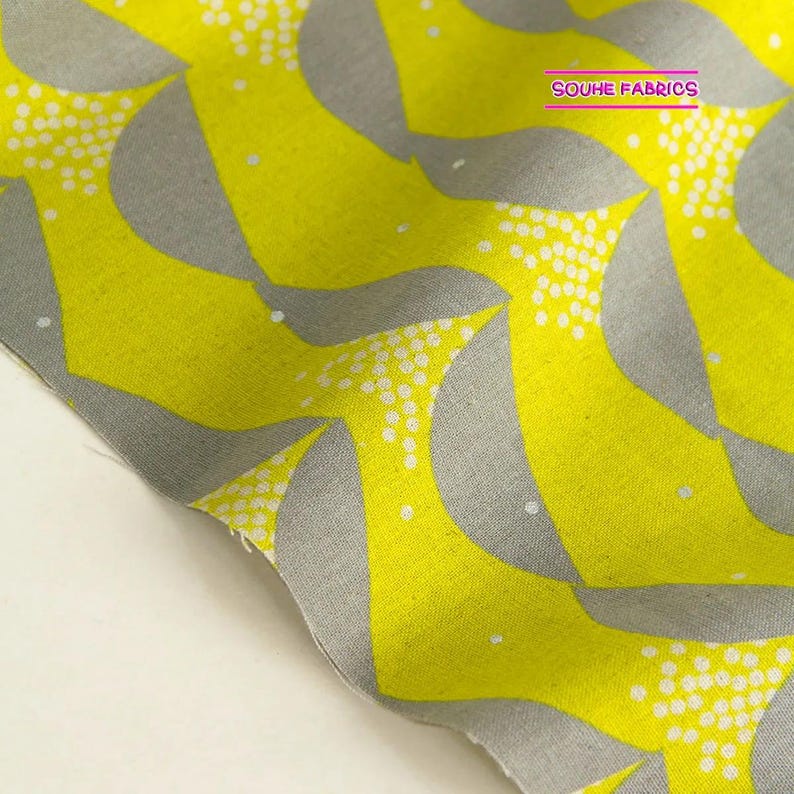 May include: Yellow fabric with a gray and white geometric pattern. The pattern features repeating curved shapes with white dots.