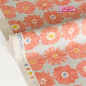 May include: A close-up of a light blue fabric with a repeating pattern of pink flowers. The fabric has a white border with the text "DEPART" and "MADE IN JAPAN" printed on it. The fabric is folded over, revealing the white border.