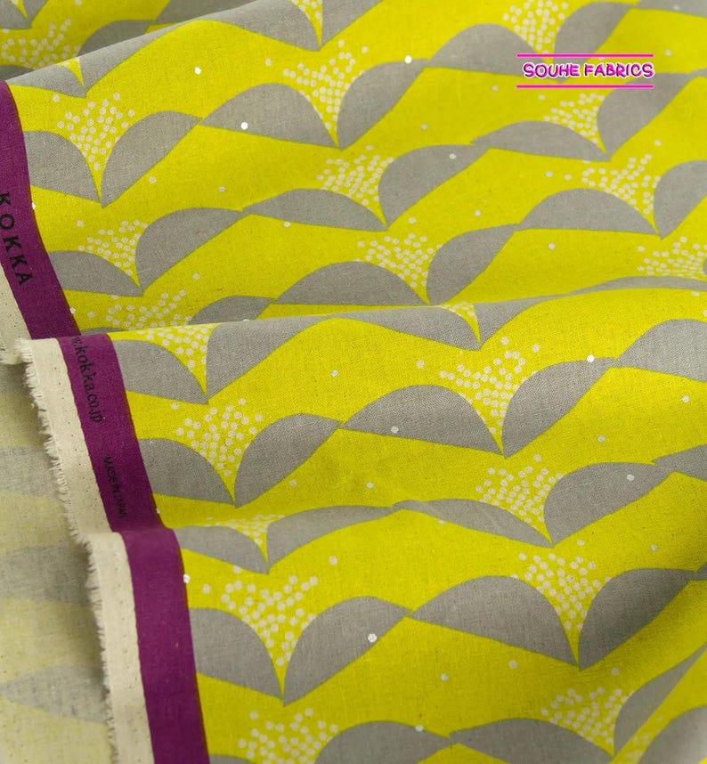 May include: Yellow fabric with a gray and white geometric pattern. The fabric has a subtle sheen and is perfect for quilting, sewing, and crafting.