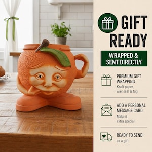 Op de afbeelding: Een grillige, oranje keramische plantenbak in de vorm van een sinaasappel met een gezicht, groen blad en handvat. De plantenbak heeft een verdrietige uitdrukking en staat op een houten oppervlak. De afbeelding bevat ook de tekst "GIFT READY" en "WRAPPED & SENT DIRECTLY".