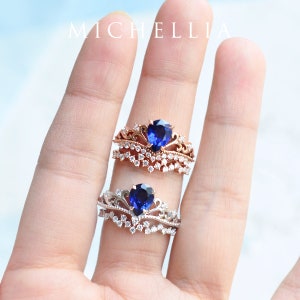 Pu&ograve; includere: Due anelli con una pietra centrale di zaffiro blu e un design a corona. L'anello superiore &egrave; in oro rosa con una fascia di piccoli diamanti. L'anello inferiore &egrave; in argento con una fascia di piccoli diamanti.