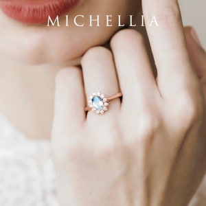 May include: A delicate ring with a blue oval gemstone surrounded by a halo of smaller diamonds. The ring is set in rose gold.