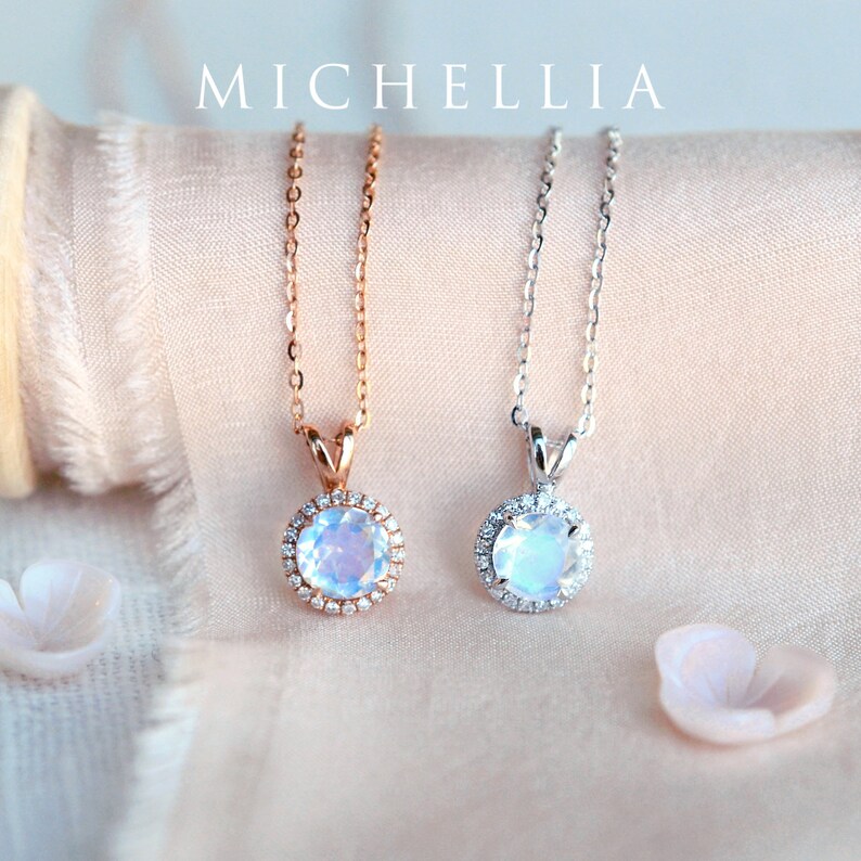 Pu&ograve; includere: Due delicate collane con ciondoli in pietra di luna. I ciondoli sono circondati da un'aureola di diamanti pi&ugrave; piccoli. Una collana ha una catena in oro rosa, l'altra ha una catena in argento.