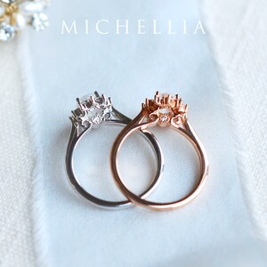 May include: Two delicate rings with a floral design and a single round gemstone in the center. The ring on the left is silver, and the ring on the right is rose gold.