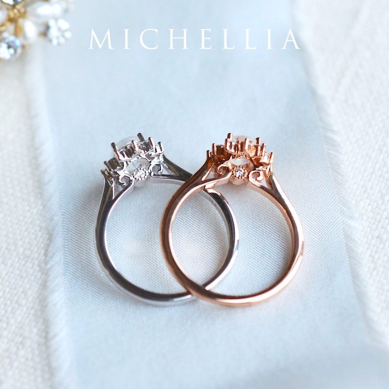 May include: Two delicate rings with a floral design and a single round gemstone in the center. The ring on the left is silver, and the ring on the right is rose gold.