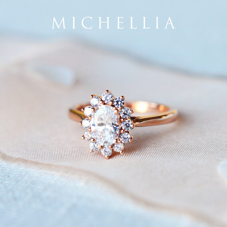 May include: A rose gold engagement ring with a large oval-shaped diamond surrounded by a halo of smaller diamonds.