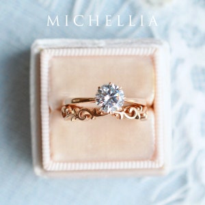 K&ouml;nnte beinhalten: Nahaufnahme eines Verlobungsringes aus Ros&eacute;gold mit einem runden Brillanten. Der Ring befindet sich in einer Samt-Ringbox. Der Markenname "MICHELLIA" ist &uuml;ber der Ringbox aufgedruckt.