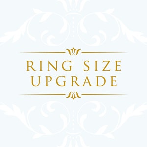 May include: A light blue background with a gold-colored frame and text that reads "RING SIZE UPGRADE". The design includes decorative floral elements in white, creating an elegant and sophisticated look. The text is centered.
