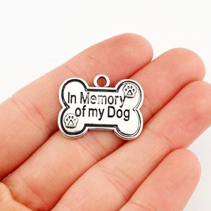 May include: Silver bone-shaped charm with the text "In Memory of my Dog" and paw prints.