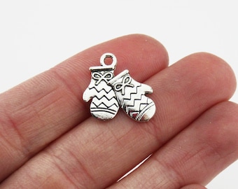 May include: Silver charm in the shape of two mittens with a chevron pattern. The mittens are joined together at the wrist and have a small bow on each.