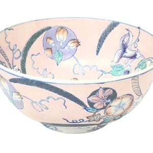 May include: A pink ceramic bowl with a floral design. The bowl features blue, green, and white flowers on a pink background.