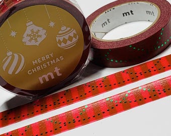 Puede incluir: Dos rollos de cinta adhesiva decorativa. Un rollo está envuelto en plástico transparente con una etiqueta dorada que presenta adornos navideños blancos y el texto "MERRY CHRISTMAS mt". El otro rollo es rojo oscuro con líneas de puntos verdes brillantes.