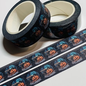 May include: Black Halloween-themed washi tape rolls and strips. The tape features a repeating pattern of a jack-o'-lantern, a spooky tree, and the word "Halloween" in white. The tape is ideal for scrapbooking and crafting.
