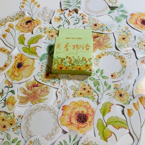 May include: A sheet of yellow floral stickers with a small box of stickers in the center. The box has the text "Flower Story" in Chinese and English. The stickers feature watercolor illustrations of flowers, leaves, and wreaths.