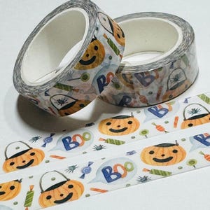 May include: Two rolls of decorative washi tape with a Halloween theme. The tape features orange jack-o'-lanterns, candy, and the word "BOO" in speech bubbles. The background is white with a variety of Halloween-themed illustrations.