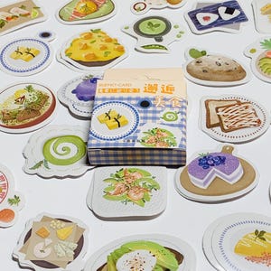 May include: A collection of food-themed stickers, including images of plates with various dishes, a box with text, and a variety of food illustrations. The stickers are colorful and detailed, with a focus on culinary themes.