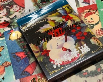 May include: A black and gold Christmas card with a snowman and holly. The card reads "Merry Christmas" and "Ice Christmas" in Japanese.