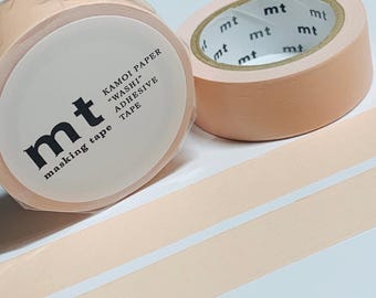 Puede incluir: Dos rollos de cinta adhesiva de color melocotón. Un rollo está parcialmente desenrollado, revelando el lado adhesivo de la cinta. La etiqueta dice "mt masking tape" y "KAMOI PAPER 'WASHI' ADHESIVE TAPE."