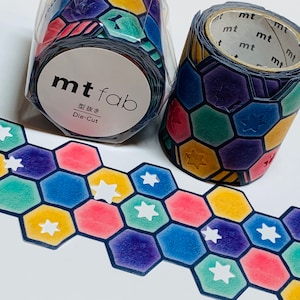 May include: Colorful die-cut washi tape rolls with a geometric pattern of hexagons and stars. The tape features a variety of colors including blue, yellow, red, and green. The rolls are labeled with the brand "mt fab" and "Die-Cut".