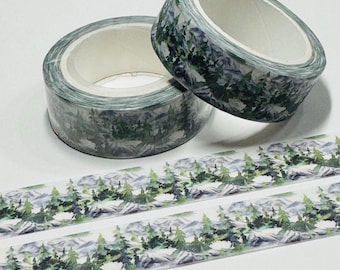 Può includere: Due rotoli di nastro adesivo decorativo washi con un motivo di montagna e foresta. Il nastro presenta un motivo ripetuto di alberi verdi, montagne grigie e uno sfondo bianco. È visibile anche una striscia del nastro.