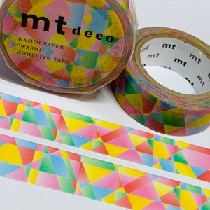 May include: Two rolls of mt deco washi tape with a colorful geometric pattern. The tape is in shades of pink, yellow, green, and blue. The packaging includes the text "mt deco" and "KAMOI PAPER 'WASHI' ADHESIVE TAPE."