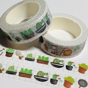 May include: Two rolls of decorative washi tape with a grid pattern and illustrations of potted plants and kitchen utensils. The tape is light gray and white, with green, brown, and black accents. Two strips of the tape are unrolled.